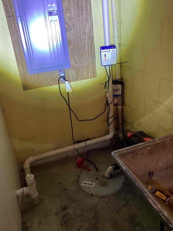 Responded to service call for non-functioning sump pump in a 60-year-old residence. Inspected the basement utility area containing the pump system, electrical panel, and associated PVC drainage pipes. Installed new control unit with monitoring display to replace faulty component. Replaced deteriorated PVC discharge pipes at exterior wall where visible weathering and joint damage were observed. System tested and confirmed operational.