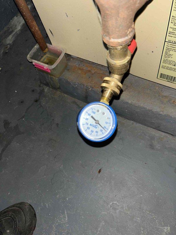 Inspected 6-year-old boiler system and identified faulty pressure relief valve with water discharge. Pressure gauge reading confirmed proper operating range, but observed corrosion at valve base requiring replacement. System controls functioning normally with temperature reading at 80°F.