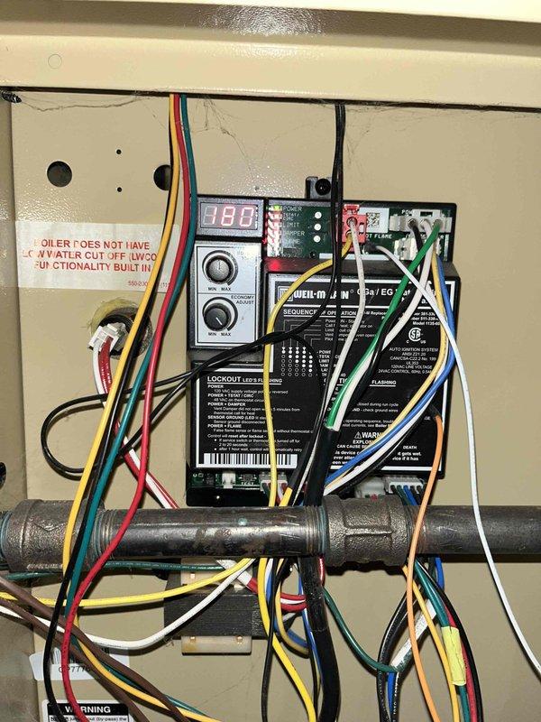 Inspected 6-year-old boiler system and identified faulty pressure relief valve with water discharge. Pressure gauge reading confirmed proper operating range, but observed corrosion at valve base requiring replacement. System controls functioning normally with temperature reading at 80°F.
