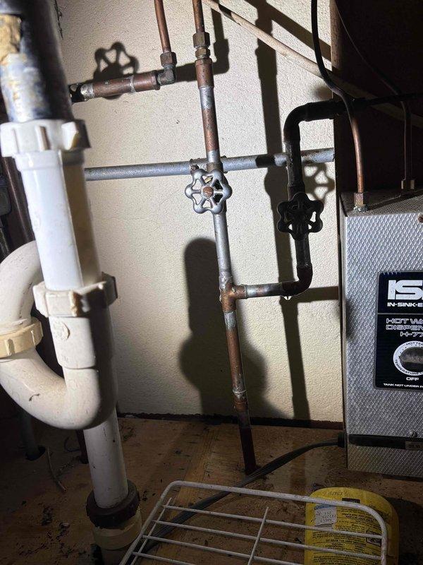 Repaired burst pipe in 100-year-old home, replacing damaged section of copper piping and securing all fittings. Inspected surrounding plumbing network including multiple control valves and PVC drainage components to ensure proper function. Confirmed water flow restoration and verified absence of leaks in the repaired system.