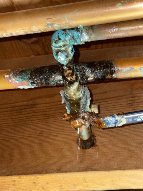 Addressed leaking copper water line in basement of 60-year-old home. Discovered significant corrosion and oxidation at pipe junction with blue-green patina (verdigris) on multiple connection points. Replaced deteriorated section and valve assembly to resolve ongoing moisture issue.