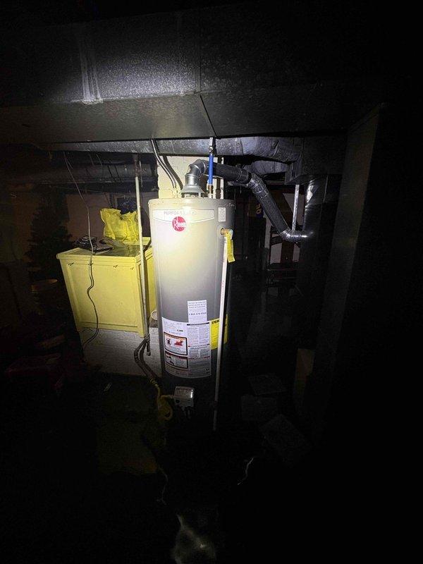 Responded to service call for basement water infiltration where customer reported backup into the house. Upon arrival, discovered significant flooding in the basement with standing water reaching several inches in depth, partially submerging appliances. Inspected the Rheem water heater system and surrounding plumbing infrastructure to identify source of leakage. Documented condition with photos for comprehensive assessment and repair planning.