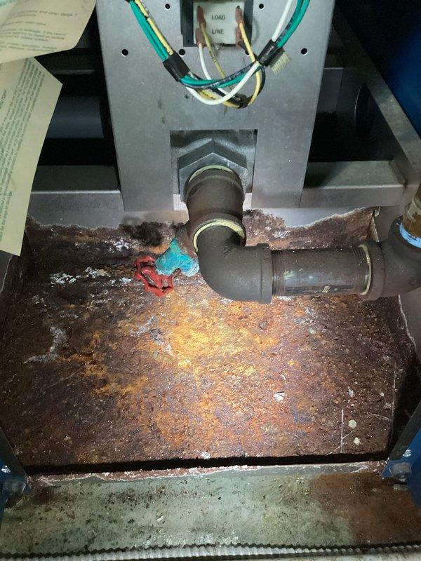 Inspected 60-year-old boiler system with significant water leakage from corroded pipe connections. Observed severe rust damage on metal basin housing and extensive oxidation on copper supply pipes. Replaced deteriorated valve and sealed leaking connection point to restore proper system function.