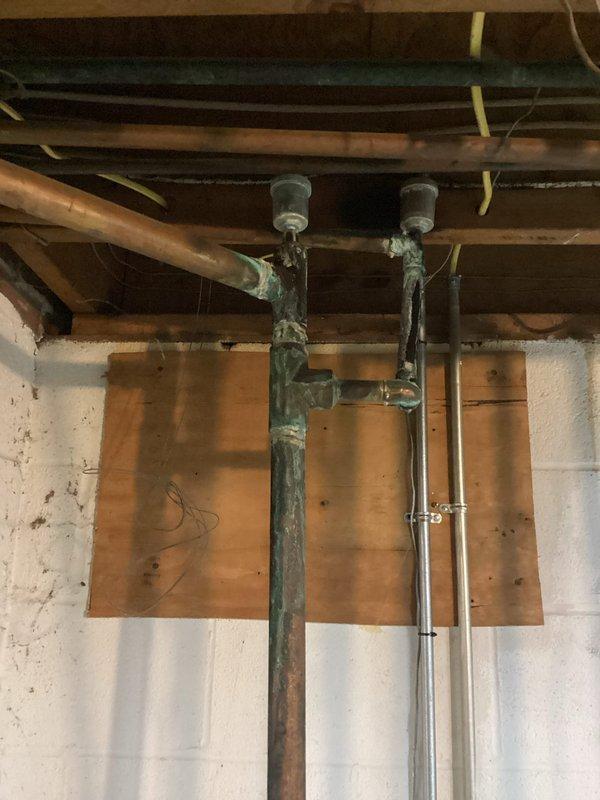 Inspected 60-year-old boiler system with significant water leakage from corroded pipe connections. Observed severe rust damage on metal basin housing and extensive oxidation on copper supply pipes. Replaced deteriorated valve and sealed leaking connection point to restore proper system function.