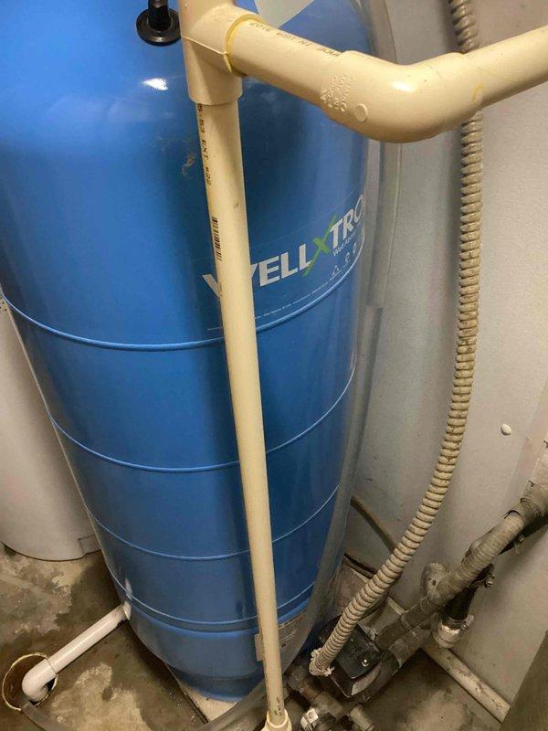 Responded to emergency service call for complete loss of water supply in 30-year-old residence. Inspected comprehensive water treatment system in basement consisting of multiple filtration tanks (blue, gray, and beige) and Wellxtrol pressure tank. Diagnosed pressure tank failure, replaced defective component, and restored water service to entire house.