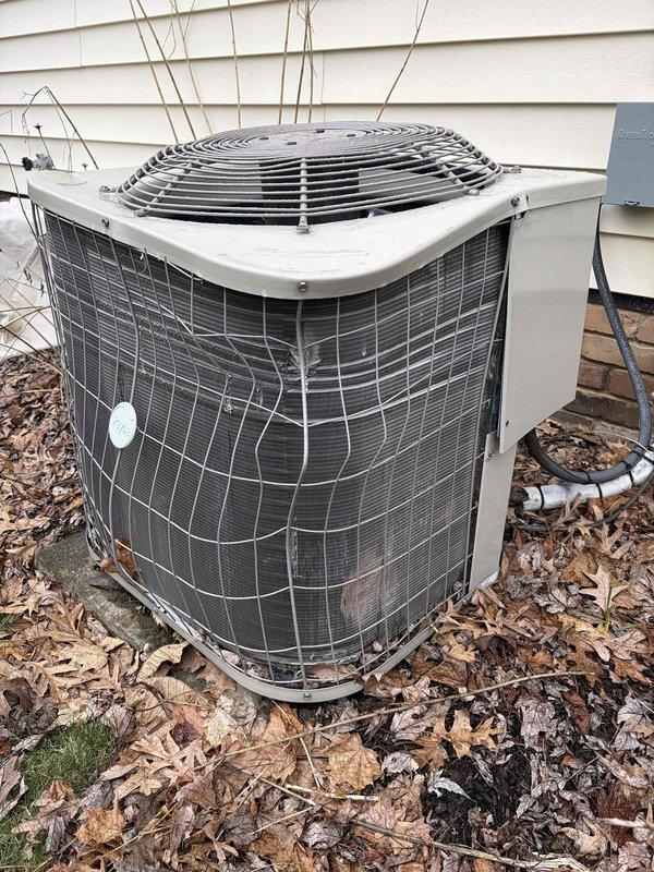 Conducted visual inspection of 5-year-old AC condenser unit showing exterior weathering and age-related wear. System was found to be operating properly despite minor cosmetic damage to the condenser housing. No service quote was provided as this was booked as an estimate only.