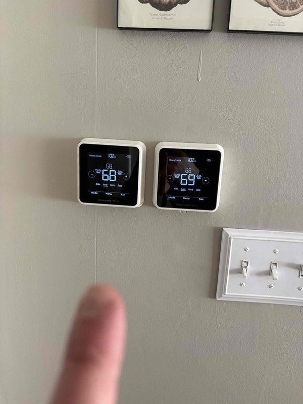 Completed inspection of existing dual-zone thermostat system and outdoor AC condensing unit for replacement estimate. Current thermostats show proper functionality with digital displays and WiFi connectivity. Exterior condensing unit exhibits signs of age with surrounding vegetation issues that could impact airflow. Recommended replacement of aging system with compatible equipment to maintain existing zoning capability while improving efficiency.