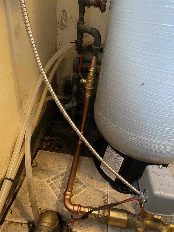 Responded to emergency service call for a 51-year-old well pump system. Inspected aging copper pipe configuration and pressure regulation assembly showing signs of corrosion and previous moisture damage. Completed necessary repairs to restore proper functionality to the well pump system, including addressing issues with pressure gauge readings and connections to the cylindrical pressure tank.