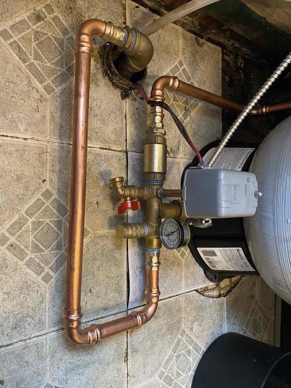 Responded to emergency service call for a 51-year-old well pump system. Inspected aging copper pipe configuration and pressure regulation assembly showing signs of corrosion and previous moisture damage. Completed necessary repairs to restore proper functionality to the well pump system, including addressing issues with pressure gauge readings and connections to the cylindrical pressure tank.