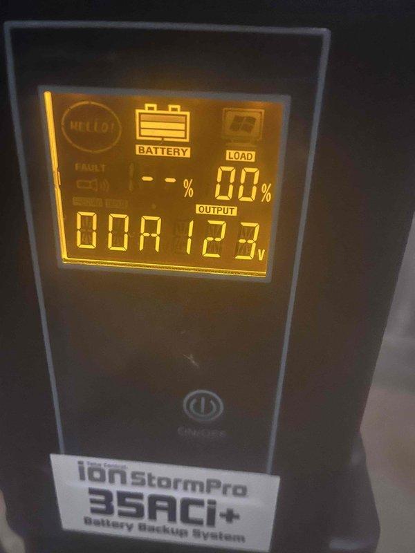 Inspected IonStormPro 35ACi+ Battery Backup System for sump pump. Diagnostic check revealed fault indicator on display panel with system showing "HELLO!" message and 0% load. Verified power connections and confirmed unit requires battery replacement to restore proper backup functionality.