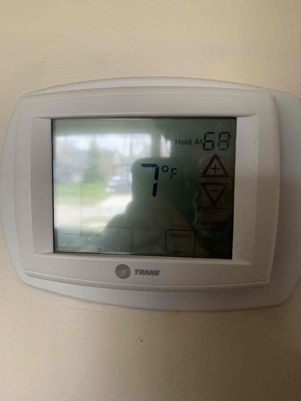 Diagnosed malfunctioning Trane thermostat displaying error code 14 with flashing red indicator light. Found unit reading 7°F despite 68°F setpoint and observed warning triangle on display. Replaced batteries and reset system to restore proper operation.