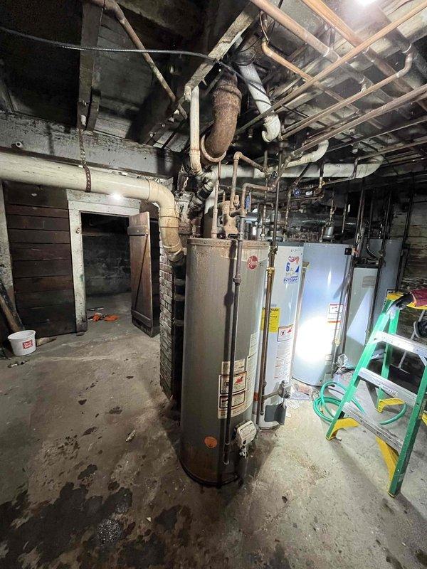 Inspected cast iron drain line serving upper apartment that exhibited active leakage in basement area. Documented existing conditions including visible water damage on concrete floor and aging plumbing infrastructure connected to water heating system. Determined job requires comprehensive repair beyond initial assessment; scheduled follow-up visit to complete necessary drainage system repairs.