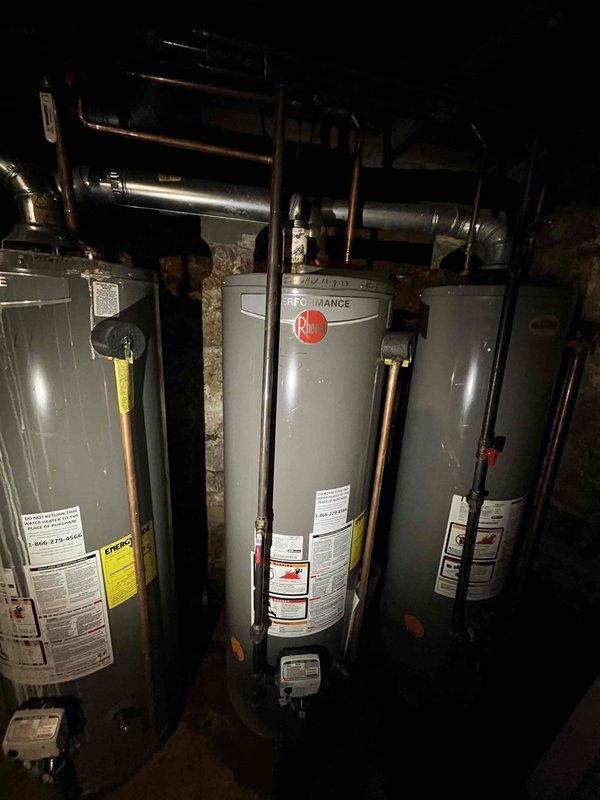 Performed gas leak detection and pressure testing on a three-unit Rheem Performance water heater system in mechanical room. Located and repaired leak at black pipe connection joint. Conducted follow-up pressure test with electronic testing device, confirming system integrity with all connections now properly sealed and operating within normal parameters.
