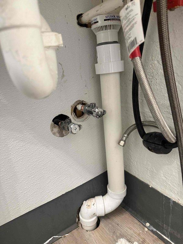Resolved water leak at commercial property by replacing deteriorated supply line connections between wall shut-off valves and sink fixture. Removed corroded fasteners and installed new braided stainless steel supply lines with proper seals, ensuring complete elimination of the leak and proper function of the Studor mini-vent system.