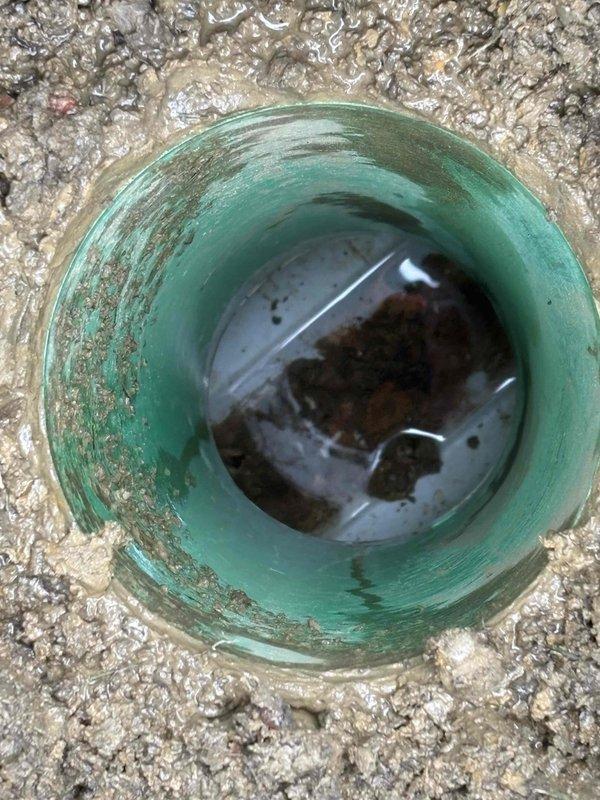 Successfully cleared a drain line using snake and jetting methods to remove debris and sediment. Visual inspection of the AH drain pipe revealed standing water with visible sediment accumulation and mineral buildup along interior walls, confirming effective restoration of proper drainage function.