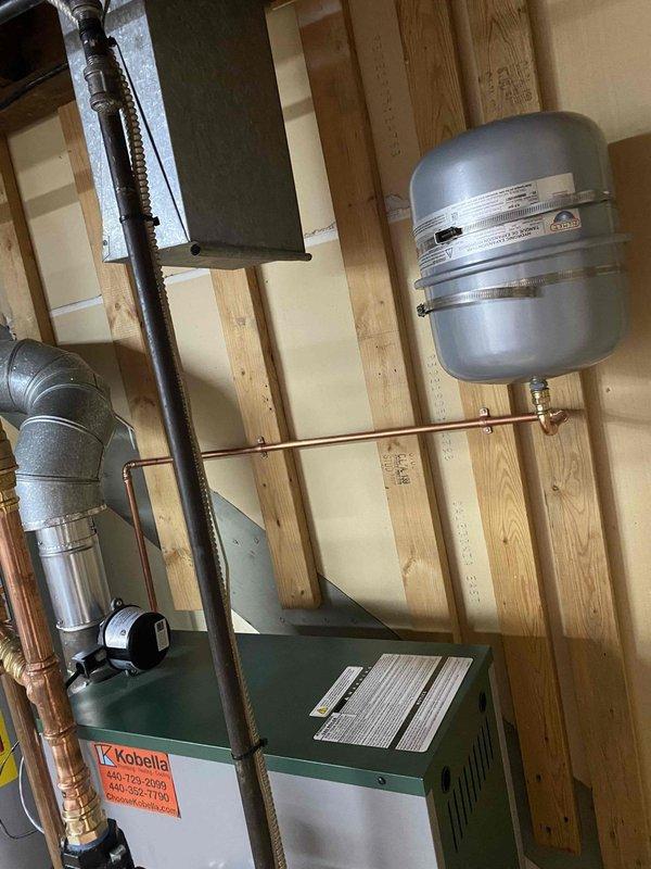 Completed installation of boiler system and State brand water heater in basement. Installation included proper connection of copper supply lines, PVC drainage, and metal ventilation ductwork. All components were properly secured to wooden framing with expansion tank and pressure vessel connections verified for optimal system performance.