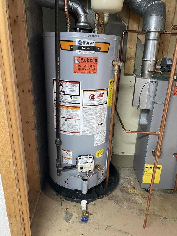Completed installation of boiler system and State brand water heater in basement. Installation included proper connection of copper supply lines, PVC drainage, and metal ventilation ductwork. All components were properly secured to wooden framing with expansion tank and pressure vessel connections verified for optimal system performance.
