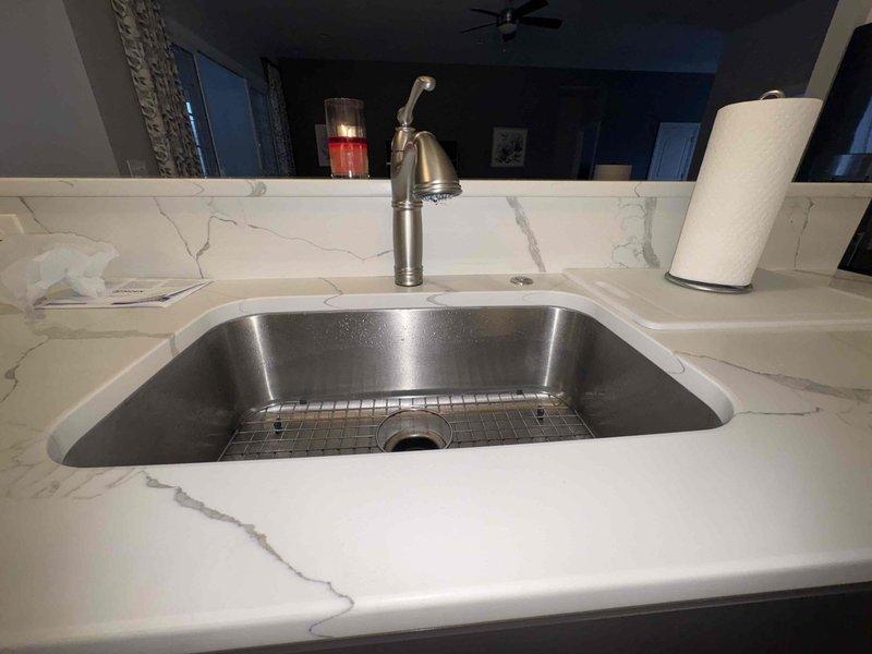 Completed return service call to replace customer-supplied kitchen faucet as previously sold. Successfully installed new brushed nickel pull-down faucet with proper connection of braided supply lines to existing plumbing. Verified proper operation of new fixture with no leaks at connection points.