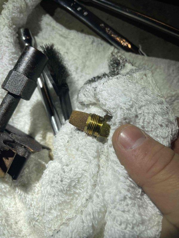 Responded to no heat call for oil furnace. Inspected and removed fuel nozzle assembly, finding clogged screen/filter which was restricting proper fuel atomization. Cleaned and replaced nozzle to restore proper heating function.