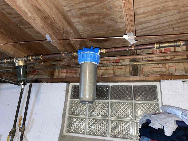 Replaced well pump pressure tank and installed new filter housings to address water treatment system issues. Identified and documented an active leak on the boiler in the concrete slab, evidenced by water staining on the garage floor trailing toward a drain. System now operating with proper pressure regulation and filtration.