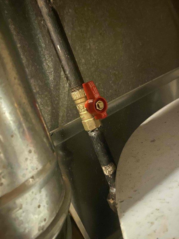 Serviced gas water heater with blue indicator light operational on control panel. Inspected and verified proper function of gas shut-off valve with red handle. No leaks detected during inspection; system operating within normal parameters.