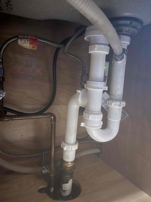 # Job Summary

Responded to service call for clogged kitchen sink with no other drains affected in the residence.

# Work Performed

Upon arrival, assessed the kitchen sink drainage system and confirmed blockage was isolated to the kitchen sink only. Inspected the P-trap assembly and drainage piping beneath the sink cabinet. Disassembled the white PVC P-trap configuration to access and clear the obstruction. Removed accumulated debris and buildup causing the blockage from the trap and drain line. Cleaned all trap components thoroughly and inspected pipe fittings and coupling nuts for proper condition. Reassembled the P-trap assembly, ensuring all threaded connections were properly tightened and sealed. Tested the drain system by running water through the sink to verify proper flow and drainage. Confirmed no leaks were present at any connection points. Inspected adjacent plumbing components including water supply lines and shut-off valves to ensure overall system integrity. Left work ar