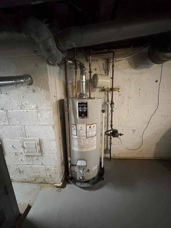 Responded to water leak complaint and conducted thorough inspection of plumbing system. Identified corroded pipe fitting in crawl space above water heater area showing significant oxidation and moisture damage. Documented conditions of water heater installation and overhead plumbing infrastructure, photographed deteriorated metal elbow joint with visible corrosion and patina indicating chronic leak source. Provided comprehensive assessment and no-charge estimate for necessary repairs.