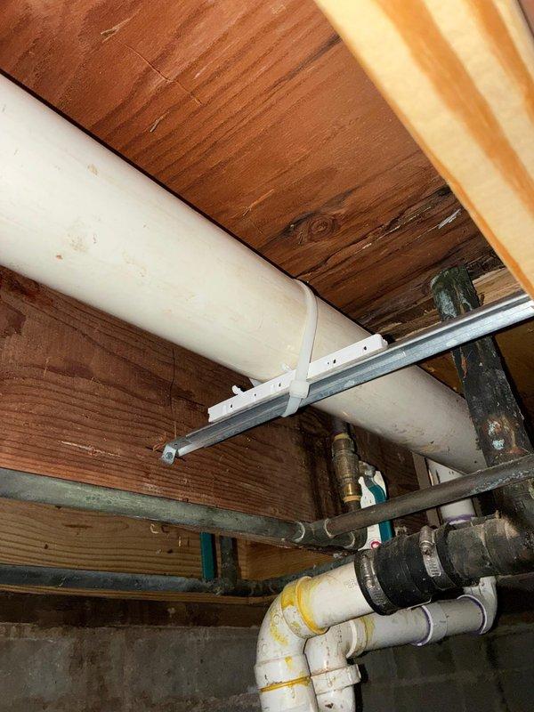 Replaced 3-inch exhaust flue pipe extending up to 30 feet in length. Installation required working in confined crawlspace area with exposed joists and existing plumbing infrastructure, utilizing hammer drill and level to ensure proper pitch and secure mounting of new flue pipe components.