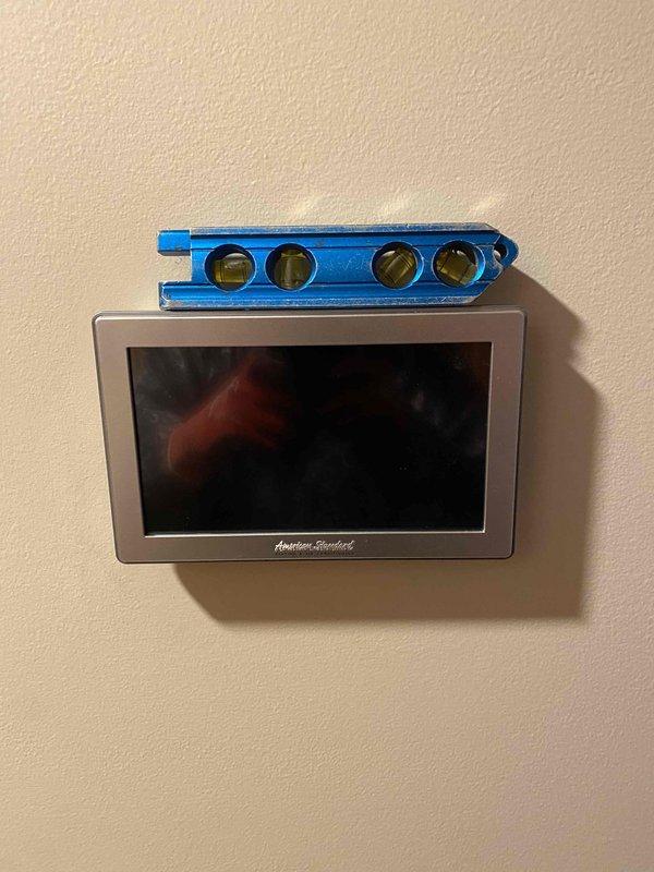 Completed furnace installation with American Standard system and integrated indoor sensor positioned in first floor living room area off kitchen. Verified proper leveling and alignment of equipment cabinet and ductwork connections using precision measurement tools. Installed and programmed wall-mounted digital thermostat control, confirmed operational status, and left additional filter media on-site for customer use.