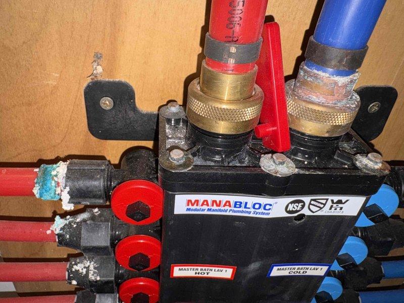 Responded to a non-functional exterior water spigot that could not be turned on or off at a 125-year-old remodeled residence. Upon inspection, isolated the issue to the outdoor spigot fixture requiring replacement. Accessed the plumbing distribution system through the MANABLOC manifold panel, which controls multiple PEX supply lines throughout the home. Shut off the appropriate hot and cold water supply valves at the manifold to isolate the exterior spigot line. Traced the red PEX supply line from the manifold to the exterior wall penetration point. Removed the failed outdoor spigot assembly and inspected the connection point for any additional damage or deterioration. Installed a new frost-free outdoor spigot with proper sealing at the wall penetration to prevent water intrusion. Verified all PEX connections at the manifold remained secure with proper insulation coverage on exposed supply lines. Restored water supply at the manifold and tested the new spigot for proper operation, conf