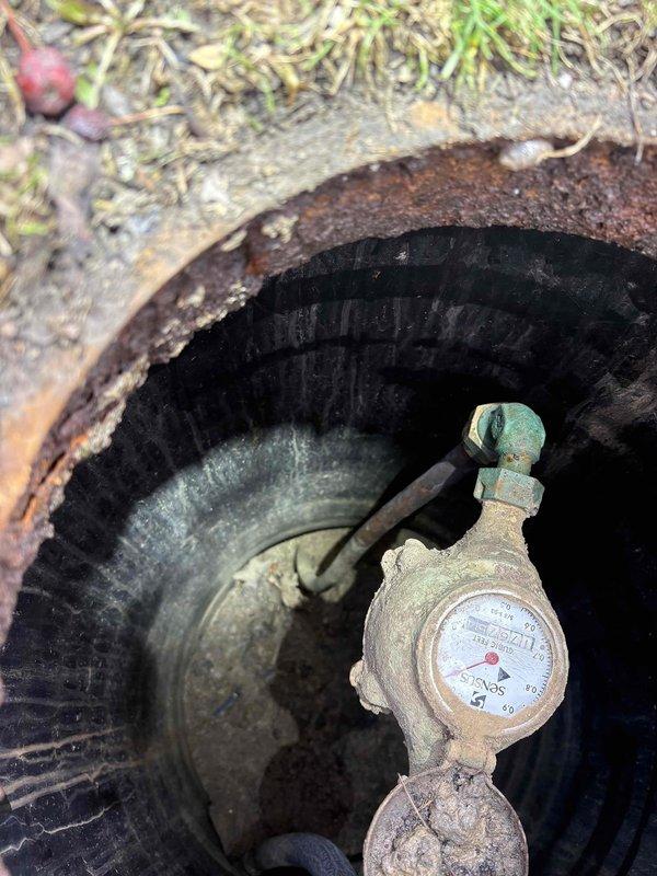 Responded to service call for suspected water leak investigation following abnormally high water consumption on recent utility bills. Conducted comprehensive leak detection inspection of the property's plumbing system and water supply infrastructure. Performed visual inspection of the water meter assembly located in the underground meter pit, checking for continuous meter movement indicating active water flow when all fixtures were off. Examined meter housing, brass fittings, and supply lines for signs of leakage, corrosion, or moisture accumulation. Inspected HVAC system condensate drain pan and surrounding areas for evidence of water intrusion or drainage issues that could contribute to water waste. Documented conditions of all inspected components with photographic evidence showing existing rust staining on equipment base and advanced corrosion on meter pit components. No active leaks detected during inspection period. Advised customer of findings and recommended continued monitorin