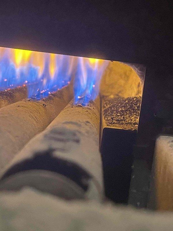 Responded to service call for boiler producing popping, banging, and gurgling noises. Upon inspection, found aging boiler system estimated at minimum 20 years old with significant corrosion and mineral buildup visible on plumbing components and piping assembly. Examined gas-fired heating appliance with ceramic log configuration and verified proper flame pattern with blue base flames and yellow-orange tips. Assessed heavily corroded piping, trap assembly, and valve components showing extensive rust staining and deterioration throughout the system. Noted mineral deposits and moisture damage consistent with long-term operation. Discussed digital thermostat upgrade options with customer for improved temperature control and system efficiency. Documented system condition with photographs for service records.