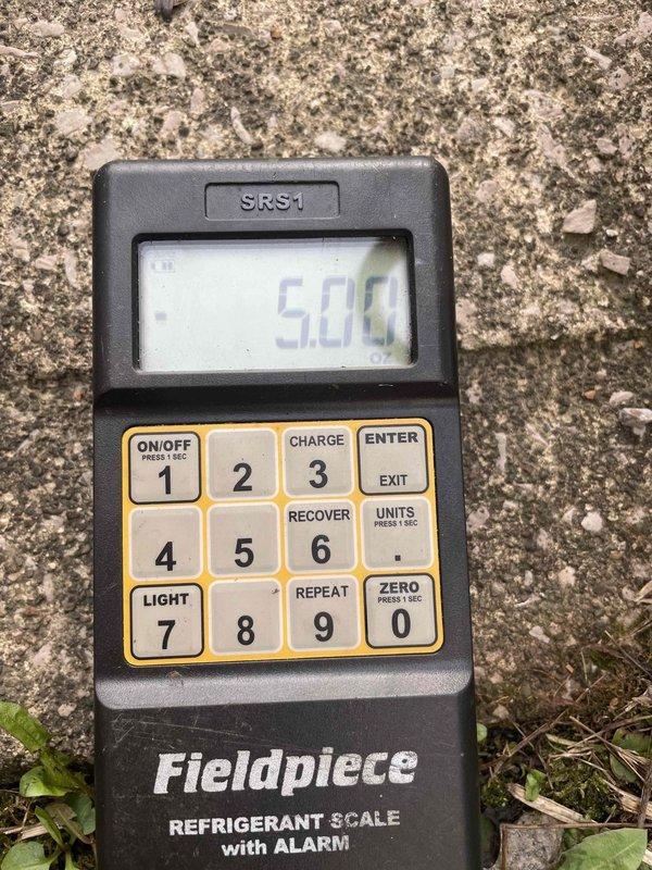 Completed cooling maintenance on air handler as part of club membership visit. Verified refrigerant charge using calibrated scale, confirming system operating at proper levels. Inspected condensate drain line and confirmed proper drainage flow through PVC discharge assembly into gravel-filled collection basin.