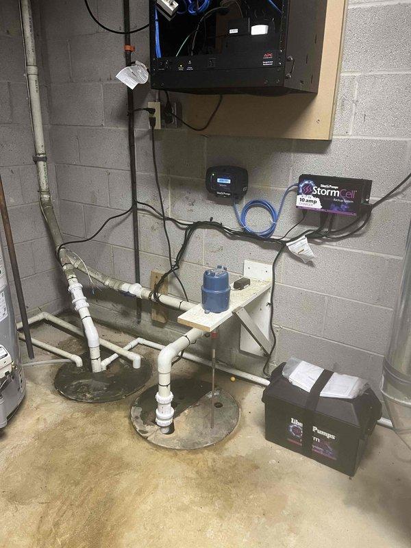 Responded to emergency basement flooding caused by failed primary sump pump in 20+ year old home. Upon inspection, found original sump pump inoperable and unable to discharge water from pit, resulting in active water accumulation on basement floor. Removed and replaced failed unit with new Liberty Pumps system. Installed complete StormCell Battery Backup System with 10-amp charger to provide redundant protection during power outages or primary pump failure. Mounted control panel and monitoring equipment to basement wall, including Storm digital display unit for real-time system status monitoring. Configured PVC discharge piping with proper vertical and horizontal routing to ensure adequate water removal. Connected backup battery unit and verified all electrical connections meet code requirements. Tested primary pump operation, float switch activation, and battery backup engagement to confirm full system functionality. System now provides dual-layer protection with continuous monitoring