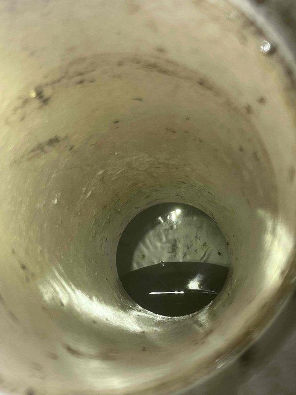 Responded to emergency call for sewage backup in residential property. Upon arrival, inspected backflow prevention device due to customer concern about potential obstruction. Investigation revealed significant accumulation of sewage and debris within the backflow assembly chamber. Interior walls showed extensive staining and residue buildup consistent with recent backup event. Dark wastewater was pooled at base of device, and interior surfaces displayed deterioration including flaking coating material and corrosion around sealing edges. Documented condition of backflow device interior showing heavy contamination and mineral deposits from prolonged exposure to sewage. Identified backflow device as source of backup issue requiring immediate attention to restore proper drainage function and prevent future sewage intrusion into residence.