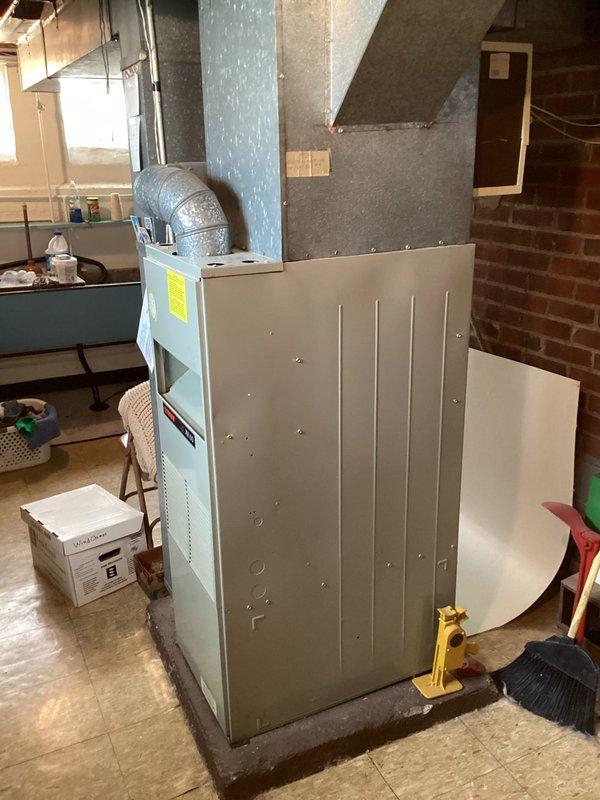 Conducted comprehensive HVAC system evaluation in basement utility area for equipment replacement estimate. Assessed existing furnace unit, ductwork configuration, and overall mechanical system layout. Documented current equipment condition, spatial constraints, and installation requirements including overhead ductwork connections, exposed brick wall proximity, and concrete floor mounting considerations for replacement system specifications.