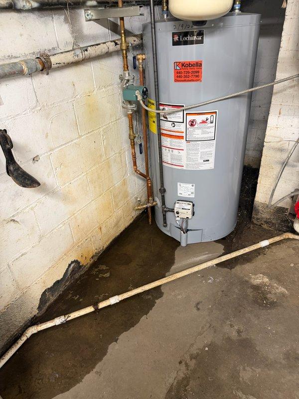 Responded to water heater failure with active leaking at base of unit. Upon arrival, found Lochinvar water heater with significant water pooling on basement floor surrounding equipment. Documented existing conditions showing water damage and confirmed unit was inoperable. Inspected connected copper piping, valves, and fittings for potential leak sources. Photographed water heater installation, surrounding plumbing connections, and extent of water accumulation for service records and warranty documentation.
