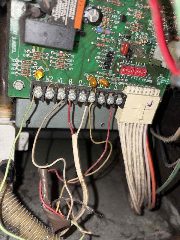 Conducted on-site evaluation of existing 20-year-old propane furnace system with air conditioning for replacement estimate. Inspected furnace control board, terminal connections, and wiring configuration to assess current system condition and compatibility requirements for new equipment installation. Documented existing system components including control board circuitry, terminal block connections, and mechanical assembly beneath floor structure to determine proper sizing and specifications for replacement HVAC system.
