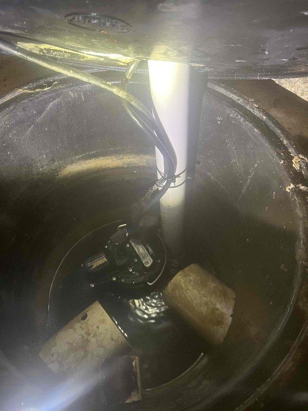 Responded to emergency call for sump pump alarm activation with water backup. Upon arrival, inspected sump pump basin and found pump mechanism submerged and non-operational. Removed debris and sediment from basin interior that had accumulated around pump housing. Tested pump motor function and verified electrical connections were secure. Identified exterior discharge line issue with water pooling at termination point. Excavated discharge area to expose piping and corrected drainage slope to ensure proper water flow away from foundation. Cleared blockage from discharge line and repositioned outlet pipe. Backfilled excavation site and restored grade. Tested complete system operation by running pump through multiple cycles to confirm proper water evacuation and alarm reset. System restored to full functionality with no further backup issues detected.