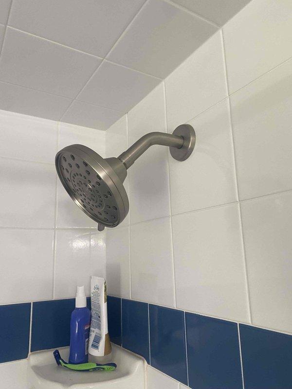 Completed installation of customer-supplied fixtures in upstairs bathroom, including toilet and shower head. Successfully installed white two-piece porcelain toilet with chrome flush lever and connected water supply line to wall plumbing, ensuring proper seating on existing tile flooring. Mounted brushed nickel multi-spray shower head with curved wall arm in tiled shower enclosure, verifying secure attachment and proper water flow. All fixtures tested and confirmed operational with no leaks detected.