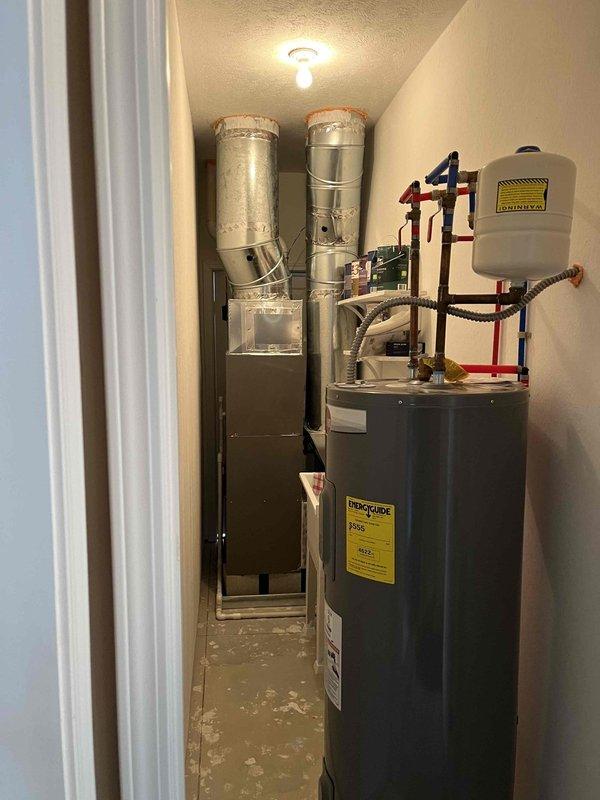 Serviced a 50-gallon electric water heater located in a utility closet alongside HVAC equipment. Inspected unit condition, connections, valves, and expansion tank mounting, verifying proper installation and operation of all plumbing components. Documented system configuration including copper piping, shutoff valves, and flex connections for service records.