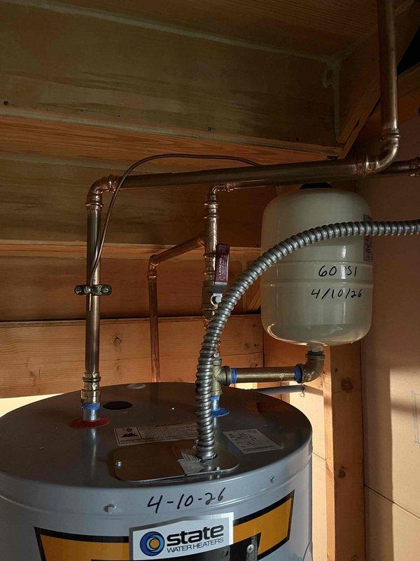 Removed existing 80-gallon electric water heater and successfully installed new 50-gallon State brand electric water heater. Modified plumbing access by removing back plywood panel to facilitate proper copper water line connections. Completed all necessary piping connections, installed expansion tank with isolation valves, and verified system operation upon completion.
