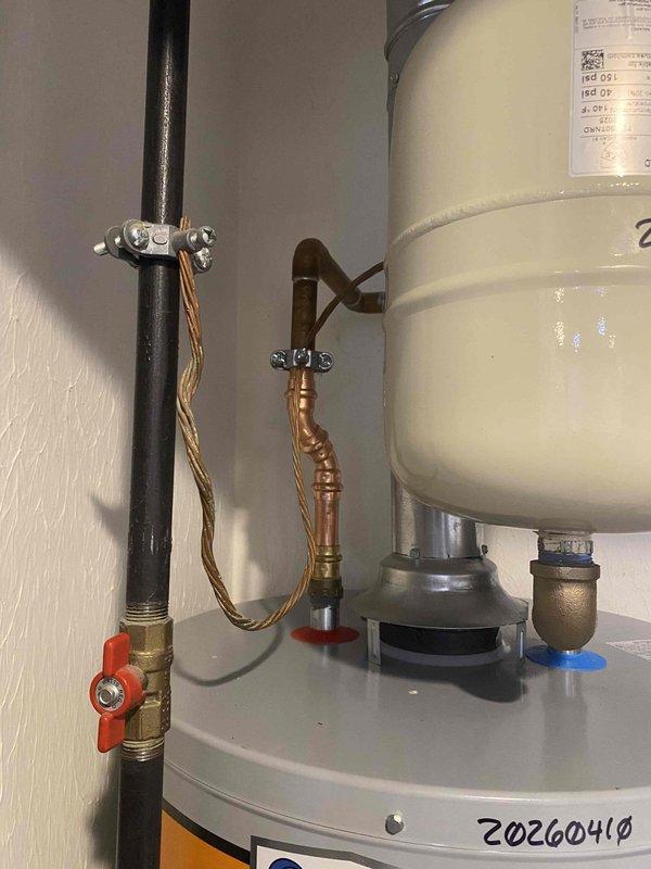 Responded to service call for water heater failure with no hot water production. Upon arrival, inspected 20-year-old tanked water heater unit that had reached end of serviceable life expectancy. Evaluated existing plumbing configuration including pressure regulation system with Calfi brass pressure regulator valve set at 0.75 PSI, pressure gauge assembly, and copper supply line connections with braided flexible connectors.

Assessed water heater installation including base mounting on gray platform, black vertical supply piping with red-handled brass shutoff valve, and dual port connections at unit base with red and blue indicators. Verified all plumbing connections, compression fittings, and metal clamps securing vertical pipe runs. Documented condition of existing low-lead compliant components and overall system configuration.

Given the age of the unit matching the home's 20-year construction date and repeated failure to maintain water temperature, recommended replacement as most co