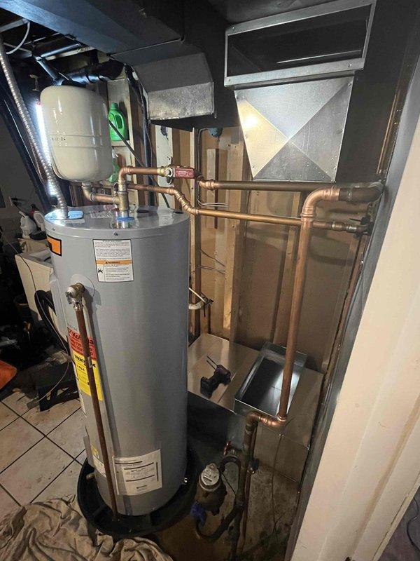 Installed 50-gallon electric Whirlpool water heater in residential utility space. Removed previously bypassed water softener from plumbing system, cut out associated piping, and re-routed water supply lines to accommodate new water heater installation. Connected all supply and discharge piping, installed expansion tank, configured temperature and pressure relief valve, and verified proper electrical connections and operational functionality upon completion.