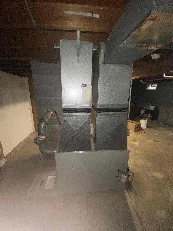 Conducted HVAC system replacement estimate for residential property with existing oil furnace and non-operational air conditioning system. Evaluated basement mechanical room conditions, documented current equipment configuration including failed AC unit and existing ductwork infrastructure, and assessed installation requirements for new HVAC system replacement in unfinished basement space with concrete flooring and exposed joists.