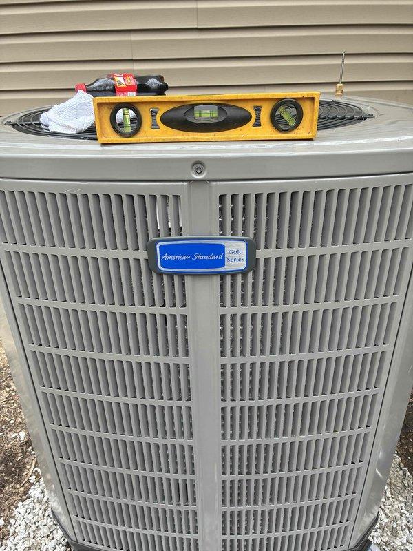 Completed full HVAC system installation including new American Standard condensing unit positioned and leveled on gravel pad against exterior wall. Unit was properly secured, leveled to manufacturer specifications, and all connections verified for optimal system performance.