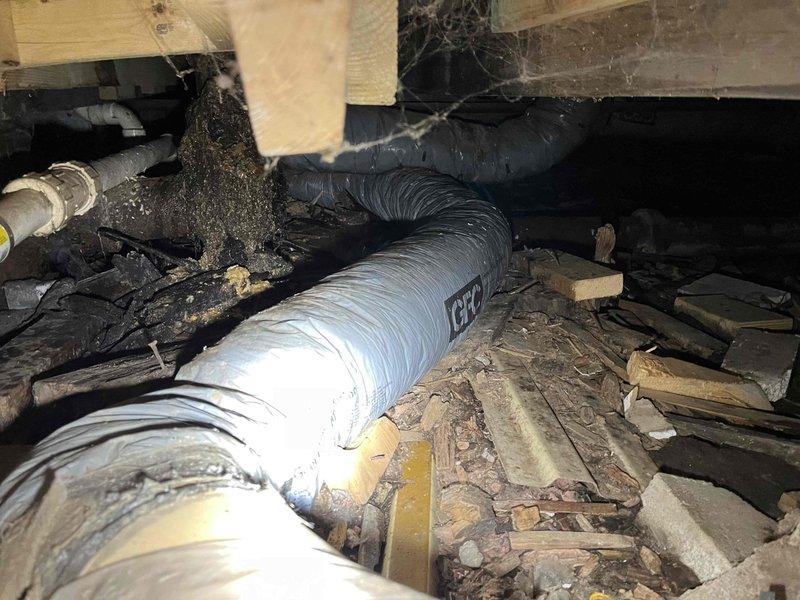 Responded to service call for clogged drain with root intrusion and leaking toilet. Upon inspection, accessed crawlspace and identified root penetration in drainage system causing blockage. Observed deteriorated plumbing infrastructure with evidence of root accumulation around drain lines. Addressed the clogged drain issue and inspected the force flush toilet for side leak. Documentation photos captured the crawlspace conditions, including affected plumbing lines, structural components, and extent of root intrusion debris.