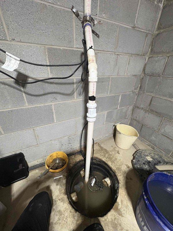 Responded to service call for failed sump pump system that was two years old. Upon arrival, found significant water accumulation on basement floor indicating pump failure. Removed malfunctioning sump pump unit from basin and discovered heavy sediment, gravel, and debris buildup that had compromised the pump's operation and led to premature failure. Cleared debris from pump basin, cleaned discharge piping system, and installed replacement pump unit. Tested new installation for proper float operation and verified adequate discharge flow through existing PVC piping. System restored to full operational capacity with basement floor water issue resolved.