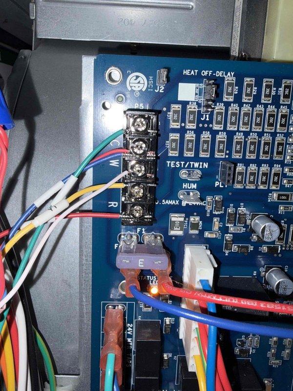 Returned to air handler to complete control board wiring installation. Connected all low-voltage wiring to the new blue control circuit board, properly terminating colored wires to designated screw terminals and ensuring secure connections with wire nuts. Verified all wire connections including thermostat wiring, heat off-delay circuits, and system controls are properly seated and functional, with board successfully powered up and LED indicators confirming proper operation.