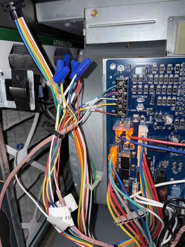 Returned to air handler to complete control board wiring installation. Connected all low-voltage wiring to the new blue control circuit board, properly terminating colored wires to designated screw terminals and ensuring secure connections with wire nuts. Verified all wire connections including thermostat wiring, heat off-delay circuits, and system controls are properly seated and functional, with board successfully powered up and LED indicators confirming proper operation.